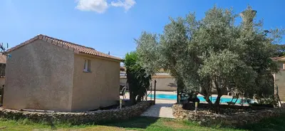 a building with trees next to a swimming pool at Bed and kitchen with pool in Aléria