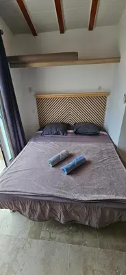 a bed with two pillows and two bottles on it at Bed and kitchen with pool in Aléria