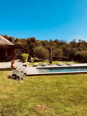 a swimming pool in a yard with chairs and grass at Peaceful Villa Between Sea And Mountain In Corsica in Lecci