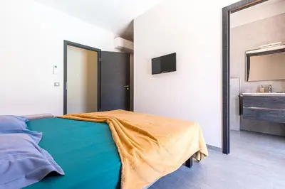 a bedroom with a bed with a mirror and a sink at La Villa Grazzoso - Piscine Privée in Sainte-Lucie de Porto-Vecchio
