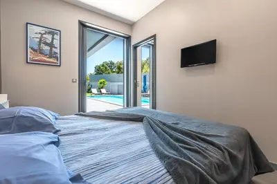 a bedroom with a bed with a tv on the wall at La Villa Grazzoso - Piscine Privée in Sainte-Lucie de Porto-Vecchio