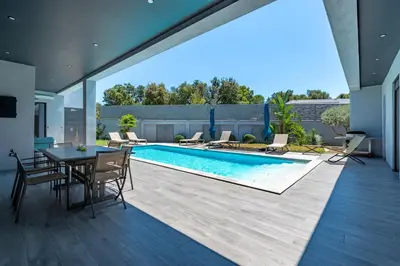 an indoor pool with a table and chairs next to a house at La Villa Grazzoso - Piscine Privée in Sainte-Lucie de Porto-Vecchio