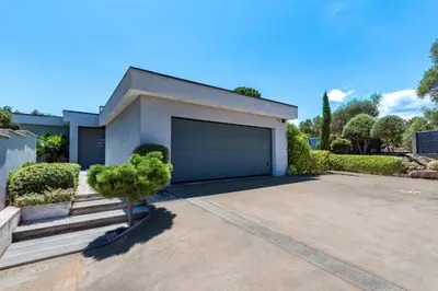 a house with a garage with a tree in the driveway at La Villa Grazzoso - Piscine Privée in Sainte-Lucie de Porto-Vecchio