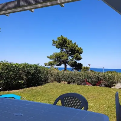 a blue table and chairs with a tree and the ocean at Villa A7 Aulyna - Vue mer climatisée in Cervione