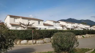 two white chairs sitting at a table in a yard at Villa A7 Aulyna - Vue mer climatisée in Cervione
