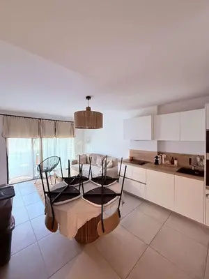 a kitchen with a table and chairs in a room at Appartement neuf Porticcio in Porticcio