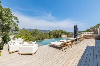 an outdoor deck with lounge chairs and a swimming pool at Villa Monte Sereno Pinarellu in Pinarellu