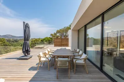 a wooden deck with a table and chairs and an umbrella at Villa Monte Sereno Pinarellu in Pinarellu