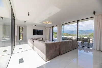 a living room with a large couch and glass windows at Villa Monte Sereno Pinarellu in Pinarellu