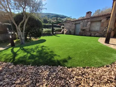 a yard with a green lawn and a stone building at Casa di Sognu in Porto-Vecchio