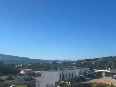 a view of a building with mountains in the background at Porticcio in Grosseto-Prugna