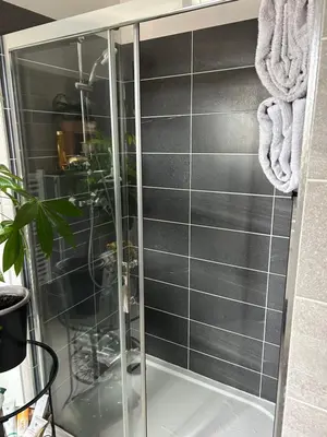 a glass shower with black tiles in a bathroom at Porticcio in Grosseto-Prugna