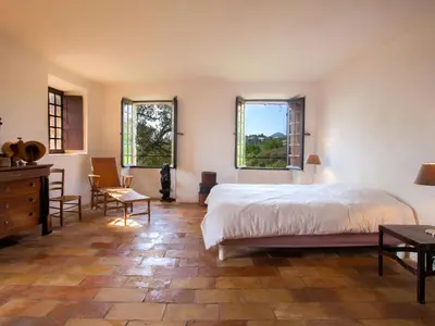 a bedroom with a bed and a desk and two windows at Holiday Home Formicaccia by Interhome in Cervione