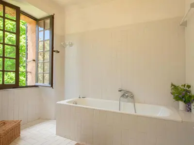 a white bathroom with a tub and a window at Holiday Home Formicaccia by Interhome in Cervione