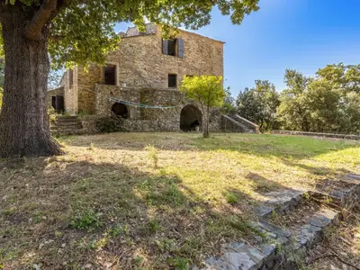 an old stone building with a tree in the foreground at Holiday Home Formicaccia by Interhome in Cervione