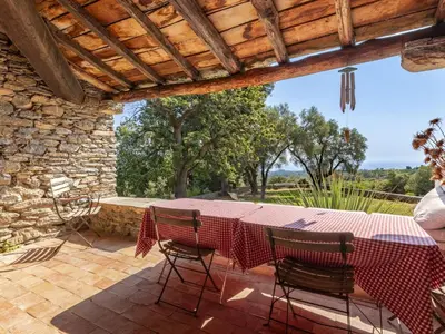 a table and chairs on a patio with a stone wall at Holiday Home Formicaccia by Interhome in Cervione