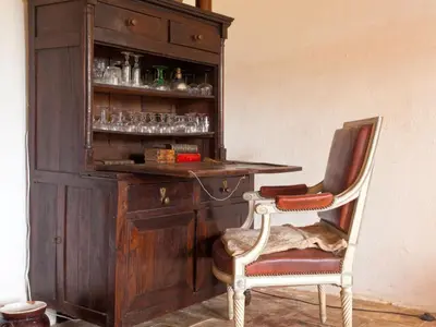 a chair sitting next to a cabinet with glasses on it at Holiday Home Formicaccia by Interhome in Cervione
