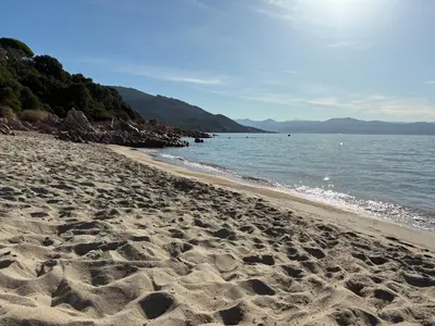 a beach with footprints in the sand next to the water at Cocon chaleureux bord de plage vue sanguinaire in Ajaccio