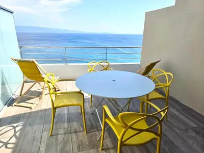 a table and chairs on a balcony with the ocean at Cocon chaleureux bord de plage vue sanguinaire in Ajaccio