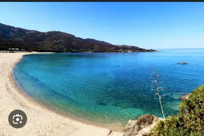 a beach with blue water and mountains in the background at Studio Corse bord de mer in Calcatoggio