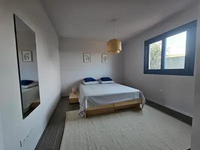 a white bedroom with a bed and a window at U Mandriolu in Prunelli-di-Fiumorbo