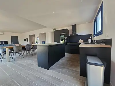 a kitchen with black cabinets and a table and chairs at U Mandriolu in Prunelli-di-Fiumorbo