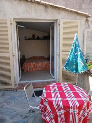 a table with an umbrella and a bed in a garage at Chambre avec SDB WC à 100 m du départ du GR20 in Calenzana
