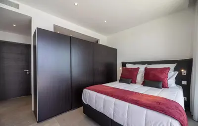 a bedroom with a large bed with red and white pillows at Villa Bianca in Zonza