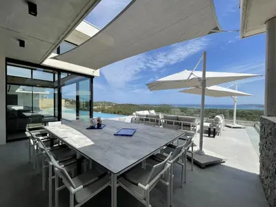 a dining room with a table and chairs and an umbrella at Villa Bianca in Zonza