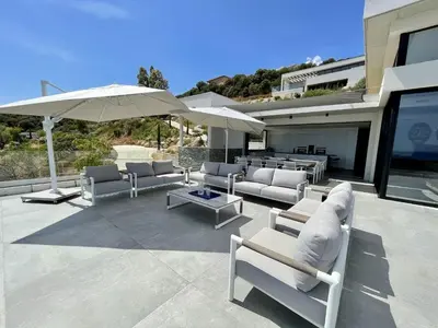 a patio with couches and an umbrella and a table at Villa Bianca in Zonza