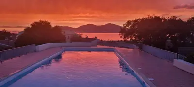 a swimming pool with a sunset in the background at Maison porticcio vue mer chez Olivier in Grosseto-Prugna