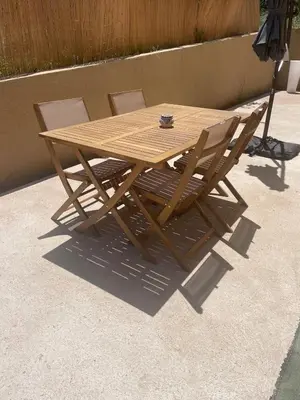 a wooden table and two chairs sitting next to a wall at T2 Cosy dans le village de Piana in Piana