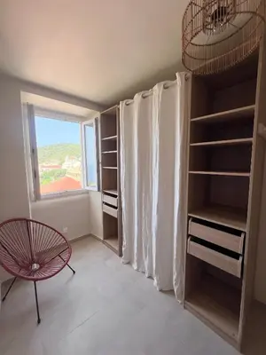 a room with a window and a table and shelves at 55m2 de charme - Vue exceptionnelle églises & mer in Cargèse
