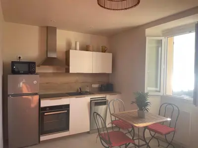 a kitchen with a refrigerator and a table with chairs at 55m2 de charme - Vue exceptionnelle églises & mer in Cargèse