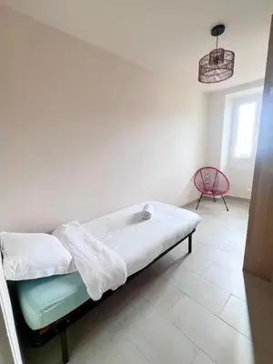 a hospital bed in a room with a red chair at 55m2 de charme - Vue exceptionnelle églises & mer in Cargèse