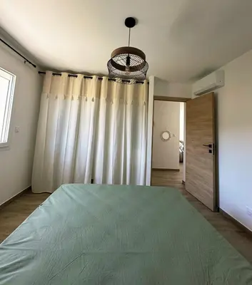 a bedroom with a large bed and a chandelier at Logement indépendant avec piscine privée in Penta-di-Casinca