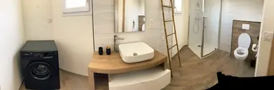 a bathroom with a sink and a washing machine at Logement indépendant avec piscine privée in Penta-di-Casinca