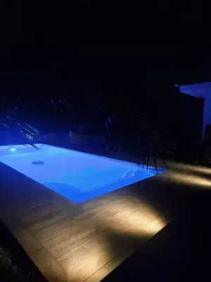 a swimming pool lit up at night with lights at Logement indépendant avec piscine privée in Penta-di-Casinca