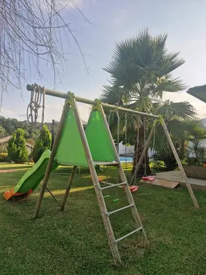 a playground with a green slide and a ladder at Logement indépendant avec piscine privée in Penta-di-Casinca