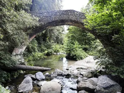 an old stone bridge over a river with rocks at Corsica sea mountain and pool in Santa-Maria-Poggio
