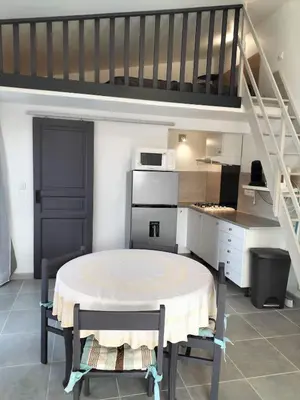 a kitchen with a table and chairs and a staircase at Studio avec mezzanine in Cuttoli-Corticchiato