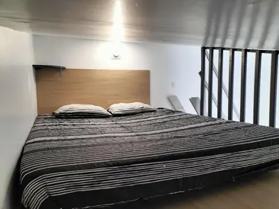 a bedroom with a large bed with a wooden headboard at Studio avec mezzanine in Cuttoli-Corticchiato