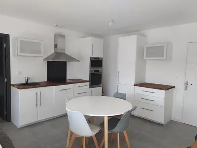a white kitchen with a white table and chairs at Proche Porticcio superbe T3 confort moderne au calme belle vue maquis et montagne in Eccica-Suarella