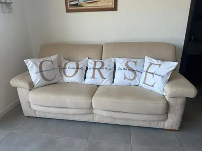 a couch with two pillows with the word comfort at Proche Porticcio superbe T3 confort moderne au calme belle vue maquis et montagne in Eccica-Suarella