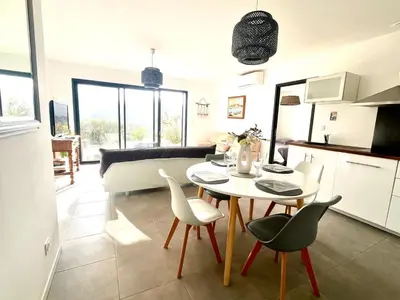 a kitchen and living room with a table and chairs at Proche Porticcio superbe T3 confort moderne au calme belle vue maquis et montagne in Eccica-Suarella