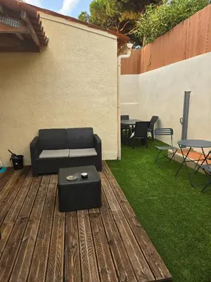 a black couch on a wooden deck with a table at Les myrtes in Propriano