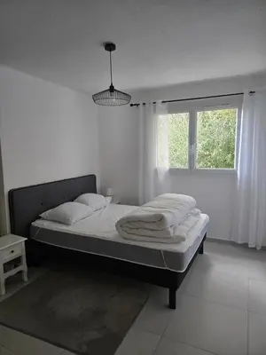 a bed in a white room with a window at Les myrtes in Propriano