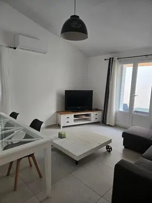 a living room with a tv and a table at Les myrtes in Propriano