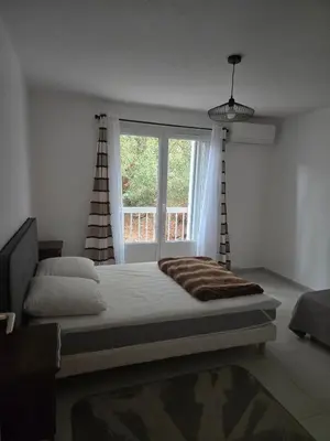 a bedroom with a large bed and a window at Les myrtes in Propriano