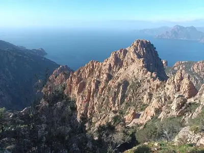 a rocky mountain with the ocean in the background at Appartement en duplex au cœur de Piana in Piana